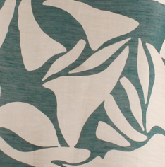 A close-up of a fabric or wallpaper pattern featuring large, abstract floral or leaf-like shapes in a muted teal green on a warm cream background.