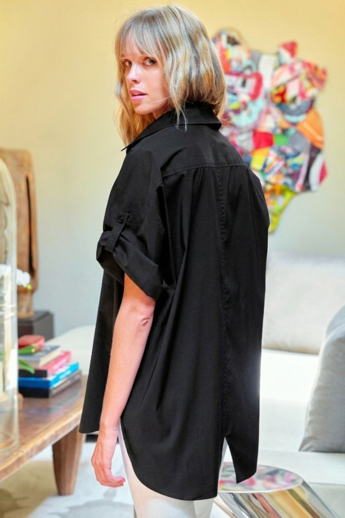 Person wearing a black oversized shirt in a living room setting