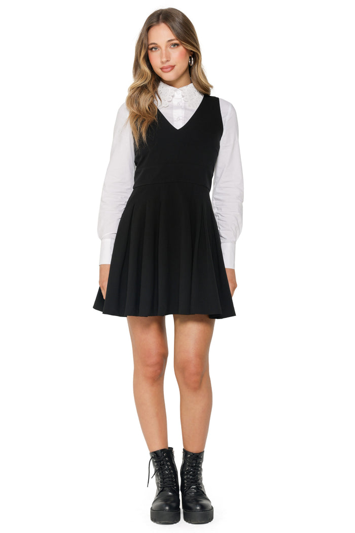 Woman wearing a black dress over a white shirt with black boots on a white background