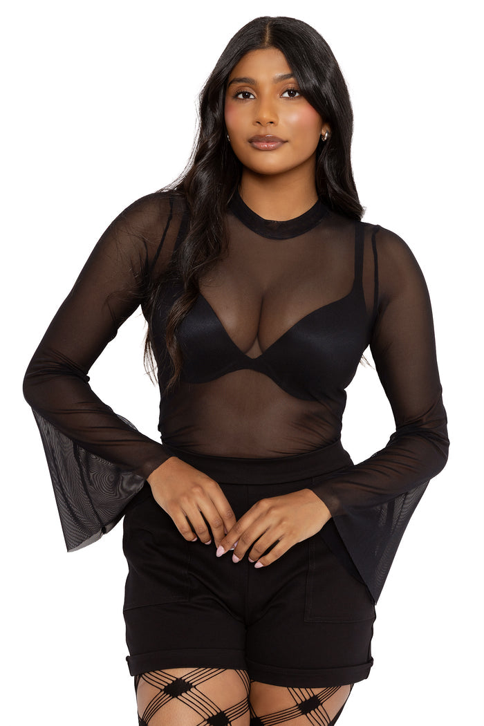 Model wearing a sheer black mesh flare sleeve top with dramatic bell sleeves and a high neckline. Styled over a black bralette with fitted black shorts and patterned tights for a gothic alt fashion look.