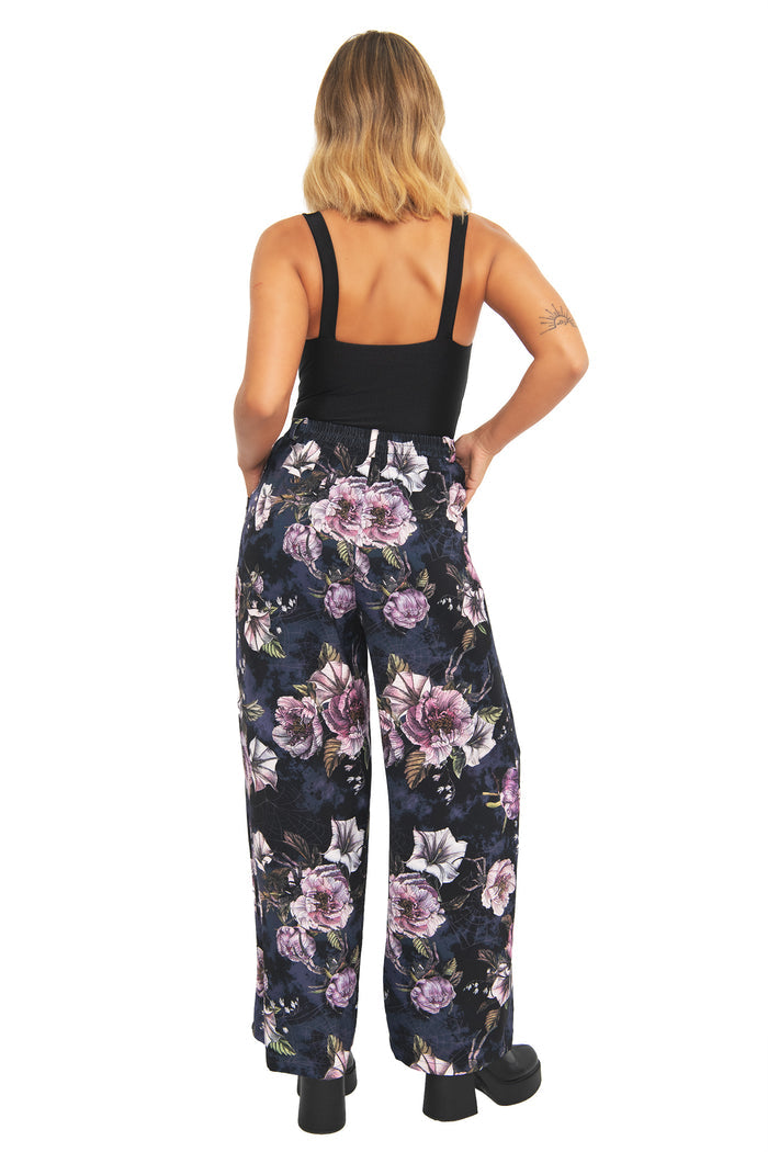 Gothic wide leg trousers featuring romantic florals and subtle hidden creepy crawlies scattered across a dark midnight print. Designed with a flattering high waist and relaxed silhouette, these corporate goth pants combine fantasy witch and modern officewear aesthetics.