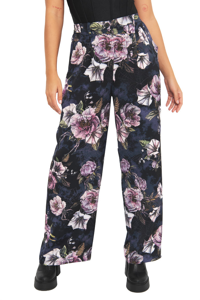 Dark academia floral pants with moody botanical artwork and subtle hidden spider details woven through the print. These corporate goth trousers combine alternative office fashion and modern witch aesthetics with a relaxed flowing silhouette.