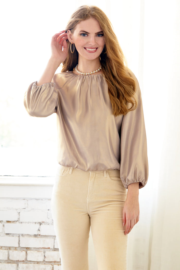 Woman wearing Cameron, a matte gold Finley blouse with blouson sleeves