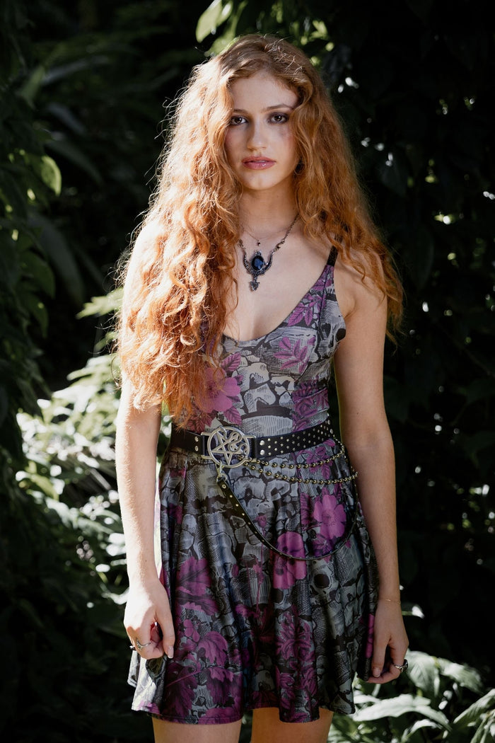 Gothic mini strappy dress with romantic floral artwork blooming through eerie skull and catacomb inspired details. This soft goth dress blends dark fairycore, whimsigoth and fantasy witch fashion with a flattering skater silhouette and delicate adjustable straps.