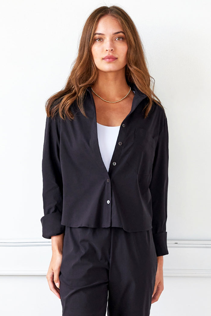 A model wearing the Finley Andie blouse, a black poplin womens blouse with a relaxed cropped shape.