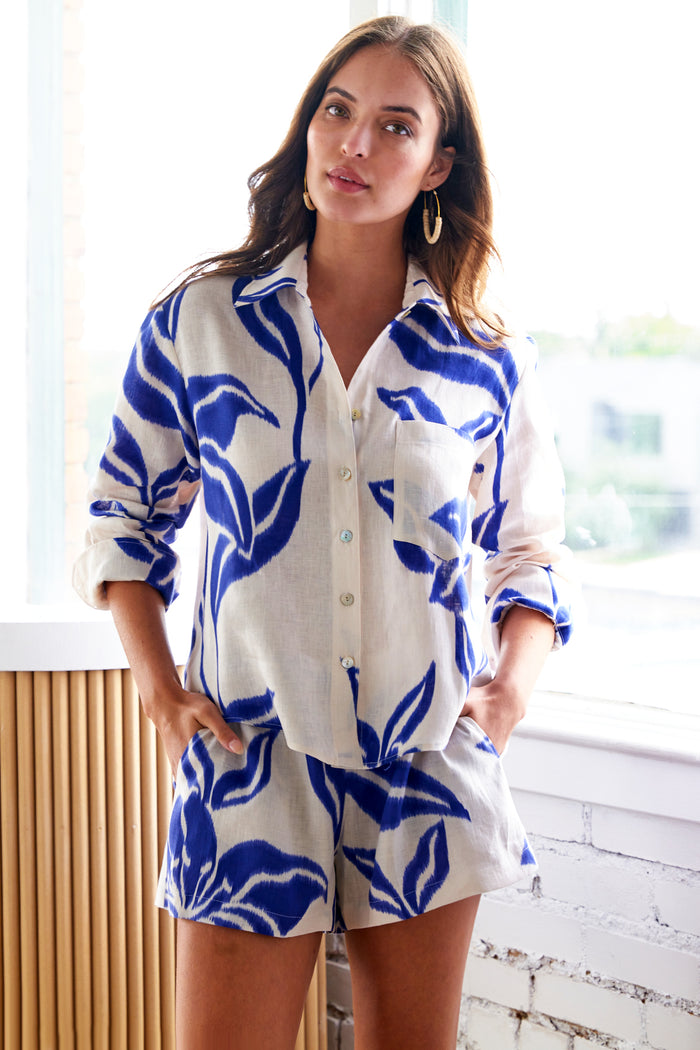 A model view of the Andie crop blouse, a 100% linen piece with long sleeves, a point collar, and raspberry floral batik print.