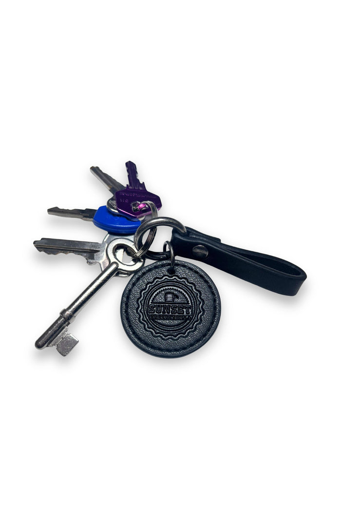 Keychain with keys and a black round tag on a white background
