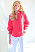 Woman wearing a red button-up shirt and white pants against a white background