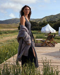Woman standing on a wooden deck with a scenic background of mountains and a tent.
