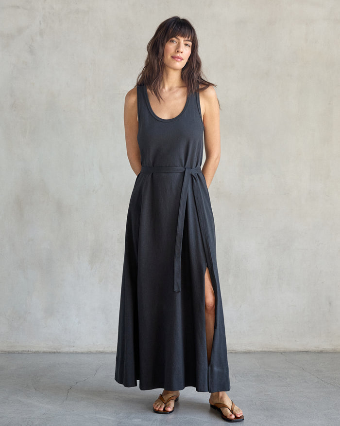 Woman wearing black tank dress in a studio with a gray background