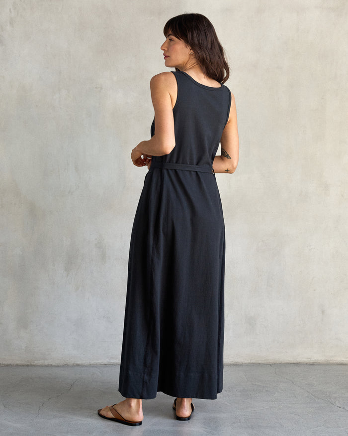Back of a woman wearing black tank dress in a studio with a gray background