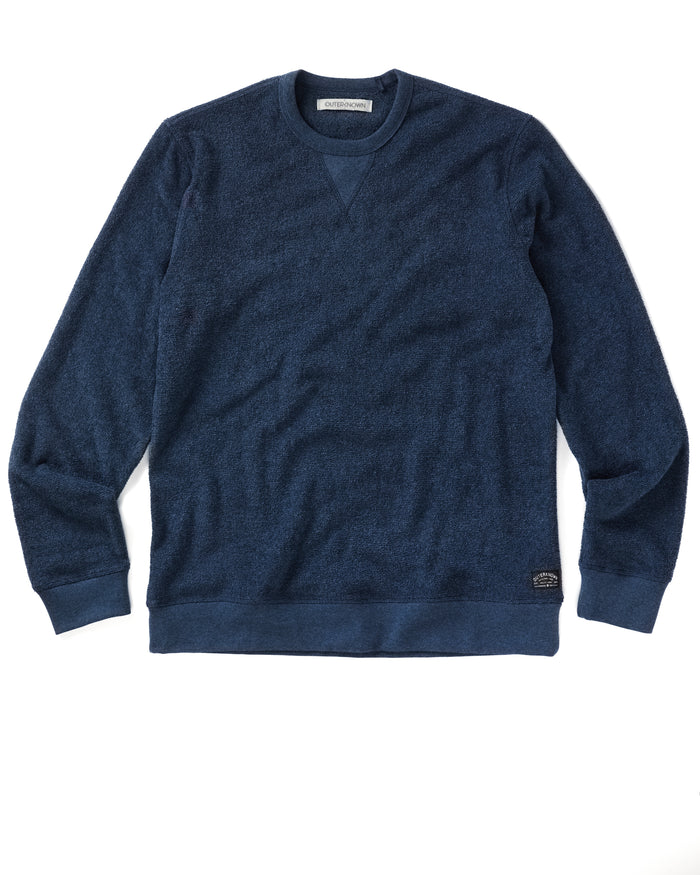 A navy blue crewneck sweatshirt made from terry toweling fabric, with a visible brand tag on the lower side.
