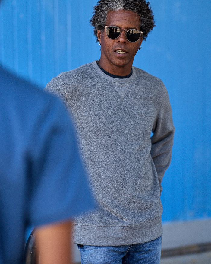 Man wearing gray crew neck sweater made from a blend of organic cotton and recycled polyester.