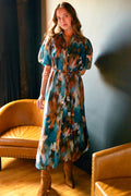 Model wearing the Finley Madeline dress, a green floral cotton voile maxi shirt dress with puff sleeves and an autumn pattern.