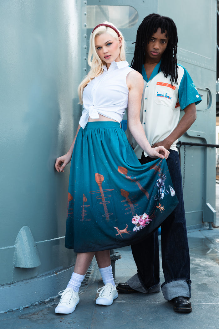 Model wearing Fallout x BlackMilk Man’s Best Friend Pocket Midi Skirt featuring Dogmeat and robot companion print on teal background.