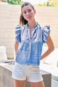 Woman wearing a blue and white striped shirt and white shorts outdoors.