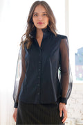 A model showcasing the Mystie long sleeve shirt featuring a high collar with ruffle neckline trim, silk organza sleeves, and black poplin in a relaxed contour.