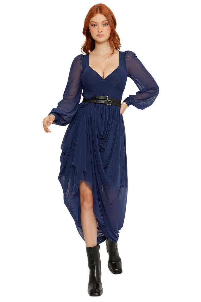 Woman wearing a blue dress with long sleeves and a black belt on a white background