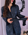 Model wearing a dark, textured jacket with a subtle floral jacquard design, tying the waist belt to create a fitted silhouette, inspired by the romantic, moody world of A Court of Thorns and Roses (ACOTAR).