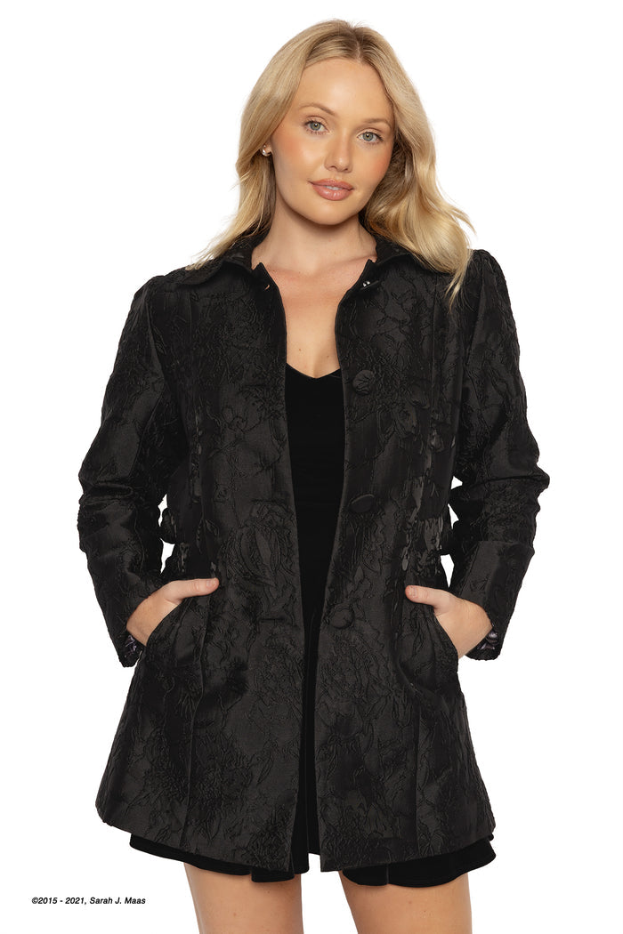 ACOTAR Night Court brocade coat in black, inspired by A Court of Thorns and Roses series by Sarah J Maas, featuring textured floral jacquard fabric, tailored fit, button front and pockets, fantasy outerwear styled over a black outfit with a dark romantic Night Court aesthetic
