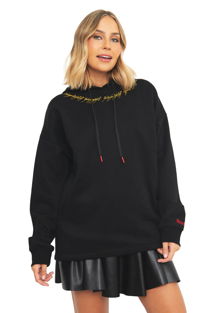 Front closeup of a model wearing the BlackMilk Lord of the Rings One Ring hoodie, showing the Black Speech Ring inscription embroidered in gold at the neckline of this oversized gothic streetwear pullover.
