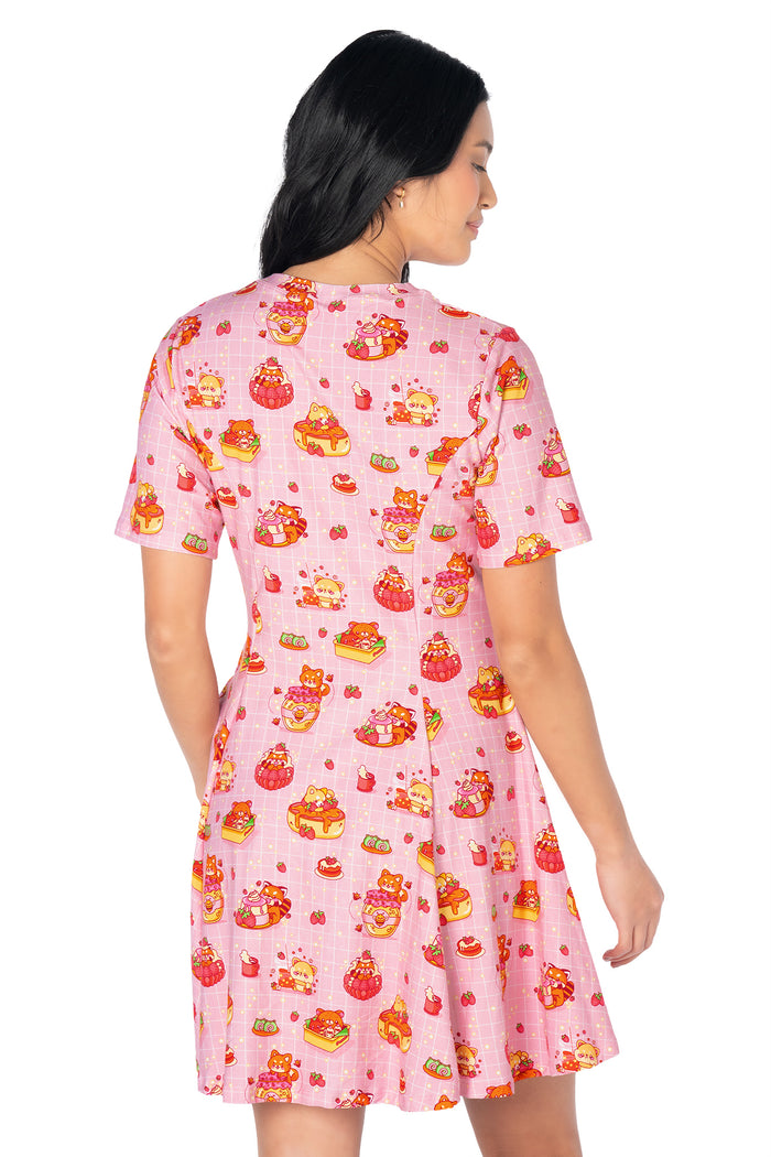 Women's pastel skater tee dress featuring whimsical café artwork with strawberries, cakes, pastries, raccoons and red pandas, crafted from soft cotton-rich fabric.