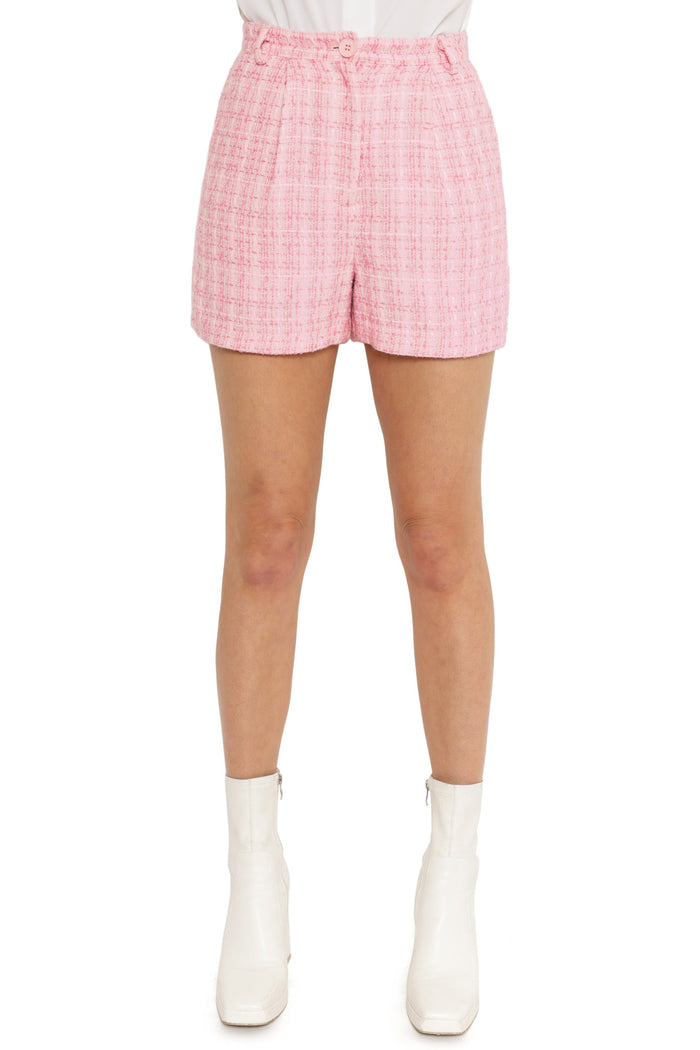 Person wearing pink plaid shorts on a white background