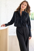A model wearing the Raffaele long sleeve blouse with a cropped fit, black poplin and silk organza, mandarin collar, and fold-back cuffs in a relaxed fit.