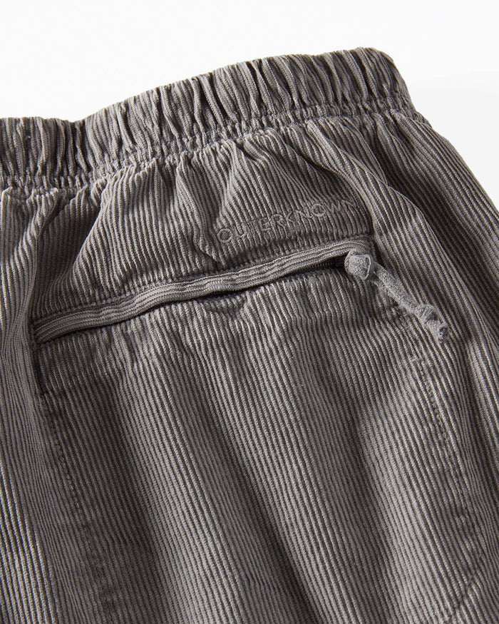 Close-up of gray corduroy pants with a brand label on a white background