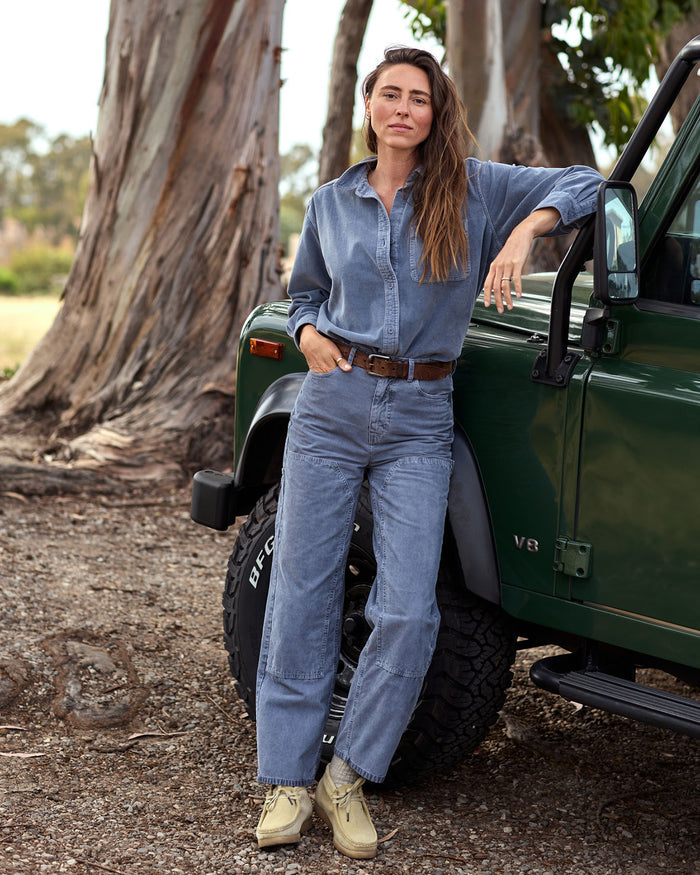 Woman standing next to a green vehicle in a natural setting