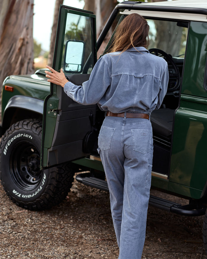 Person getting into a green off-road vehicle with trees in the background