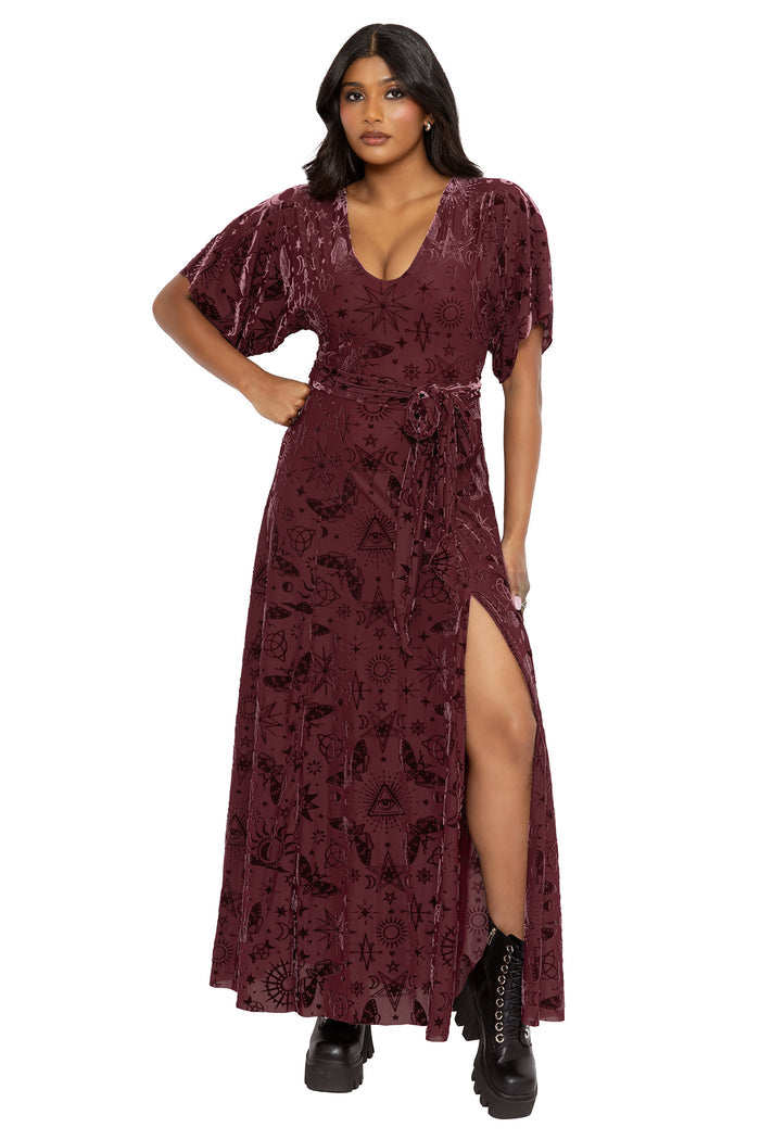 Alternative witchcore kimono dress featuring mystical spell symbols, moons, stars and occult sigils scattered across rich berry burned velvet. Designed with flowing sleeves and a fitted V-neck bodice, this fantasy witch maxi dress captures gothic and pagan fashion energy.