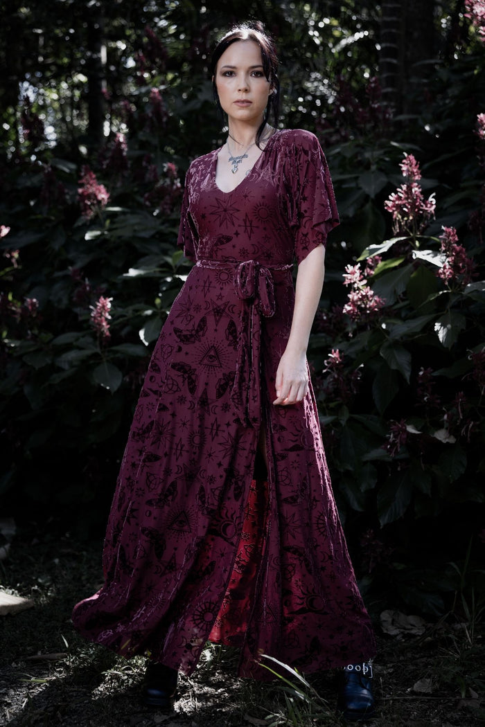 Berry red burned velvet kimono maxi dress covered in mystical sigils, celestial symbols and occult artwork. This whimsigoth maxi dress blends dark fairycore, fantasy witch and gothic fashion aesthetics with flowing kimono sleeves and a dramatic thigh-high split.
