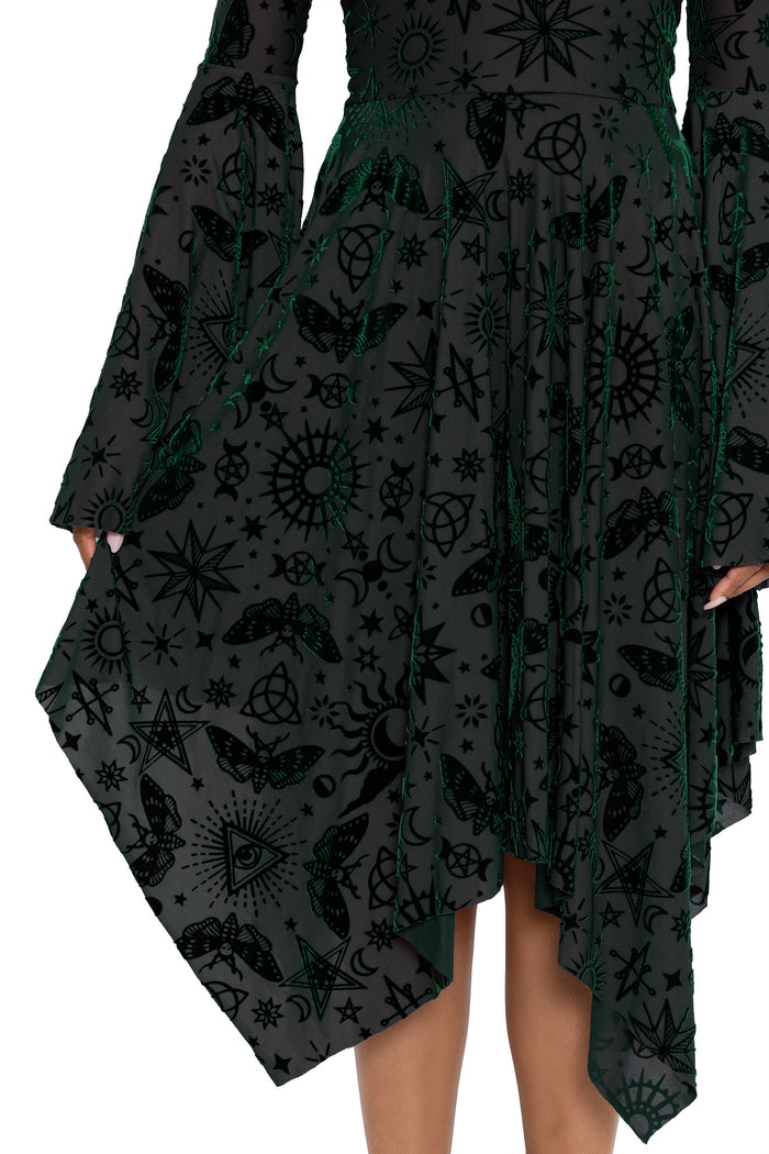 Dark fairycore handkerchief dress featuring occult symbols, stars, moons and mystical witch artwork across soft burned velvet fabric. This alternative witch dress blends gothic fashion and modern pagan aesthetics with dramatic bell sleeves and an elegant flowing silhouette.