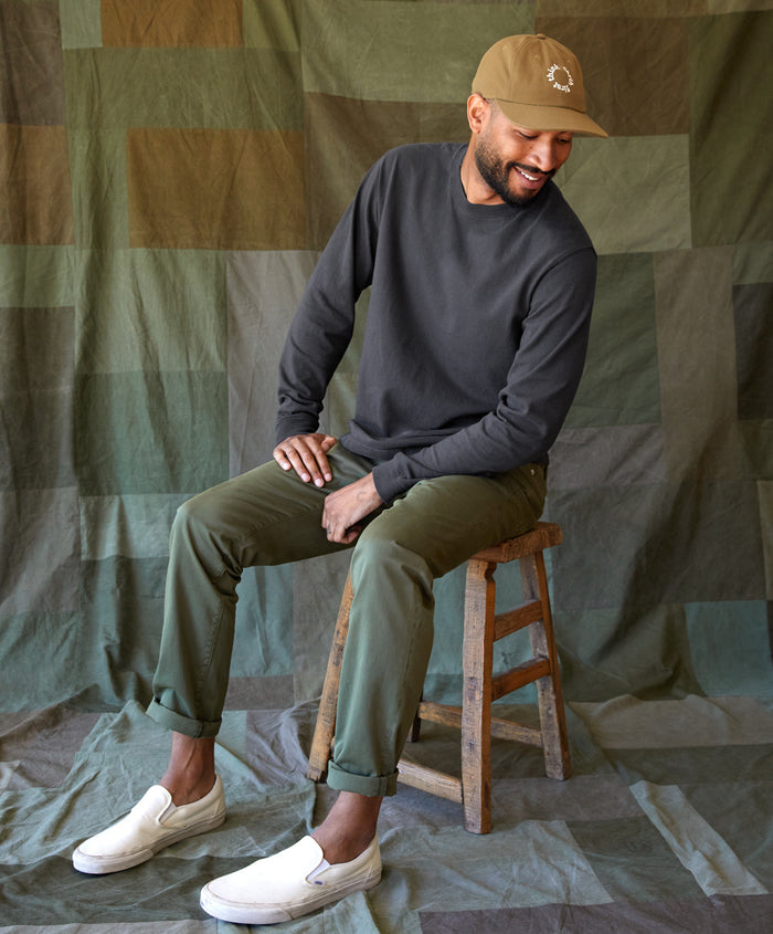 Man wearing black long sleeve t-shirt sitting on a stool in a studio