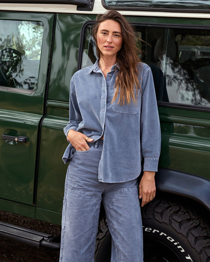 Woman in a blue outfit standing next to a green vehicle