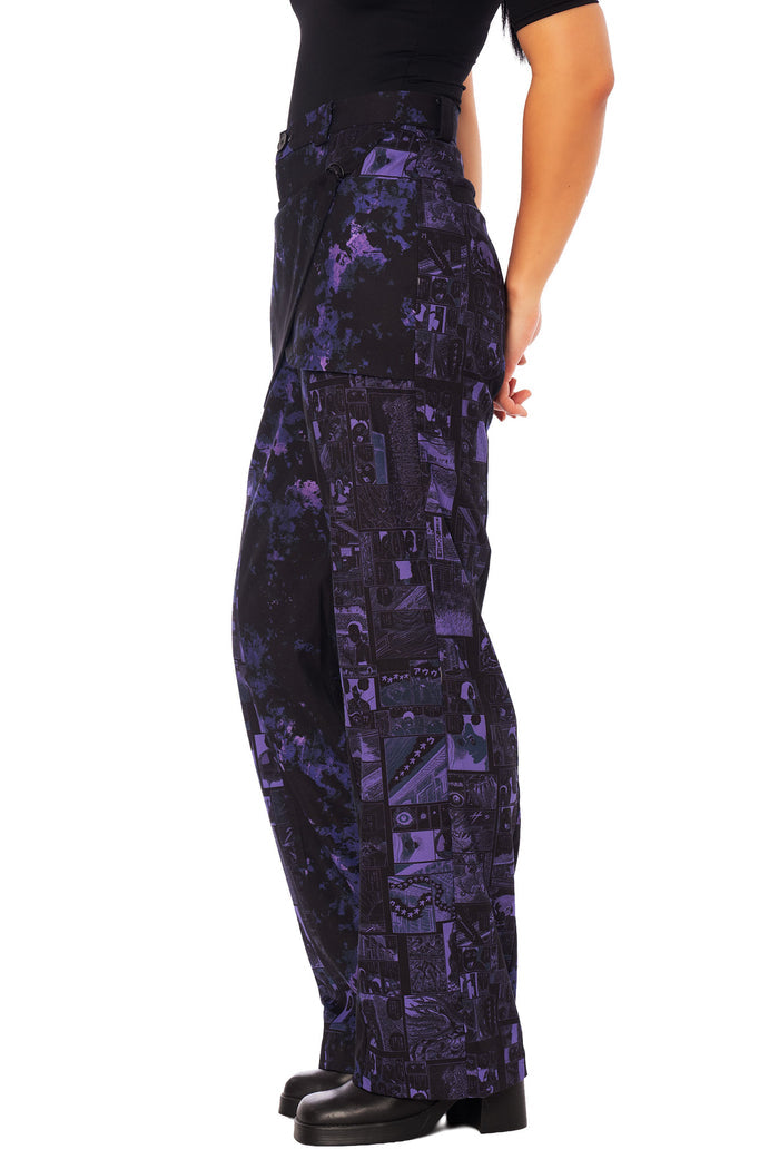 Detail of Junji Ito Uzumaki pants showing crossover front drape panel and graphic manga artwork in gothic streetwear style.