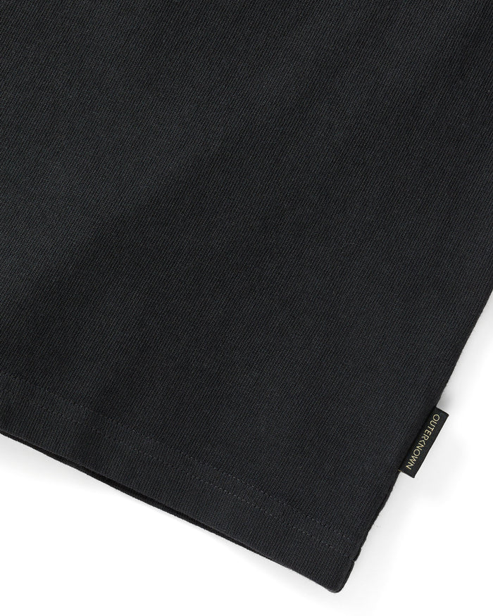 Close up of 'Outerknown' tag on the end of black short sleeve t-shirt