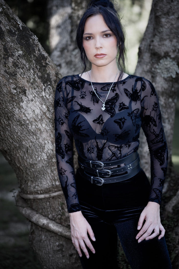Sheer black mesh long sleeve top featuring Ami Raithe moth artwork with hand-drawn insects scattered across delicate transparent fabric. This whimsigoth layering top blends dark fairycore, gothic fashion and fantasy witch aesthetics with a flattering boat neckline and fitted silhouette.