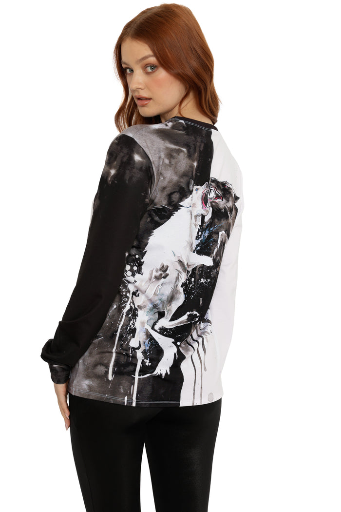 Woman wearing a black and white graphic long-sleeve shirt with a horse design on a white background