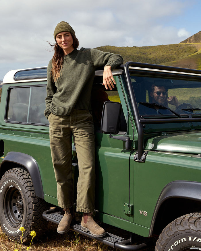 woman in green outfit standing on a green car.