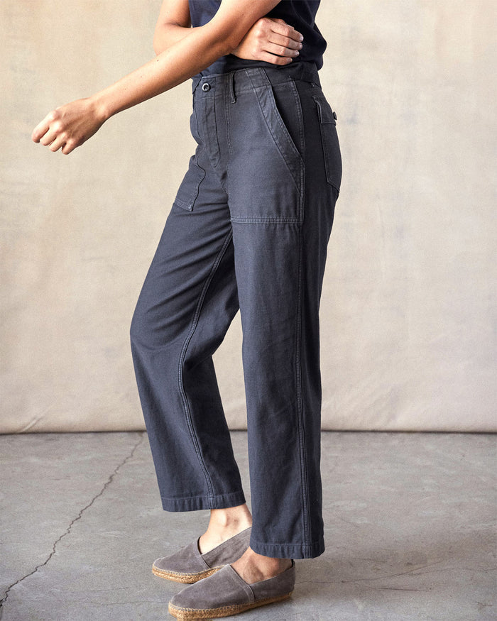 Person wearing dark gray pants standing against a plain background