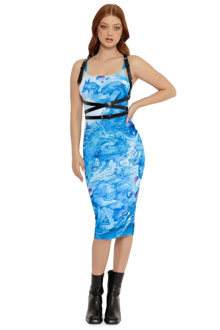 Woman wearing a blue and white patterned dress with black straps on a white background