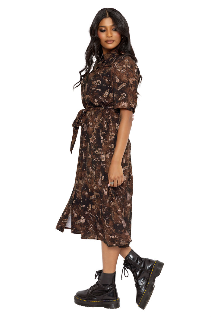 Whimsigoth midi shirt dress covered in mystical potion ingredients, butterflies, bones and witchy symbols illustrated by Ami Raithe. This gothic button-through dress combines dark fairycore, cottagecore and alternative goth fashion with a romantic vintage silhouette.