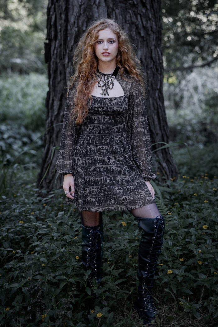 Gothic bishop sleeve mini dress with witch-history inspired artwork panels layered across sheer black mesh fabric. This whimsigoth dress blends dark academia, fantasy witch and gothic fashion aesthetics with dramatic gathered sleeves and a romantic shrug neckline.