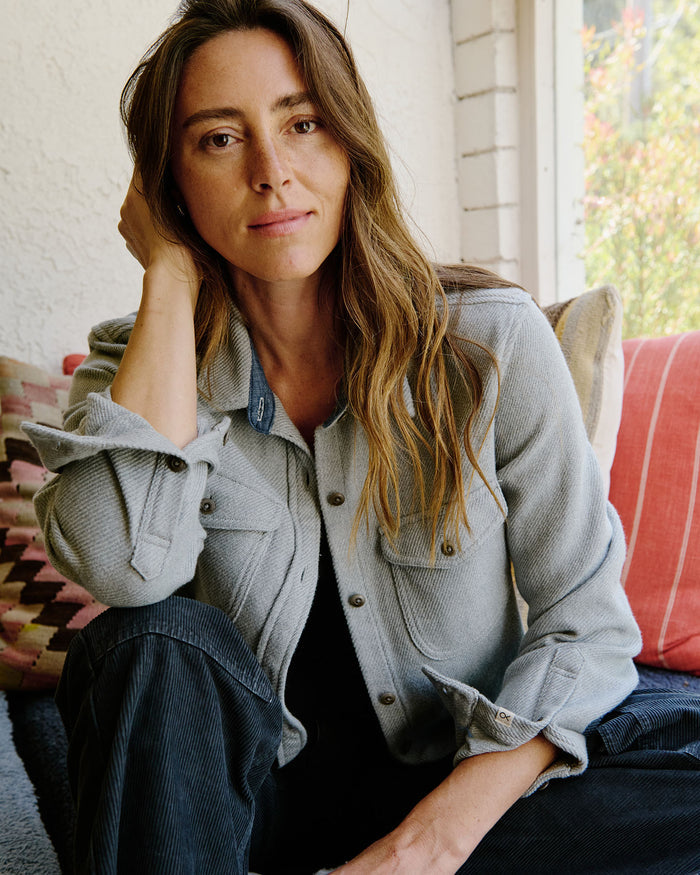 Woman sitting on a couch wearing a denim jacket with a blurred outdoor background