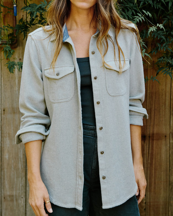 Person wearing a light gray jacket with a wooden background