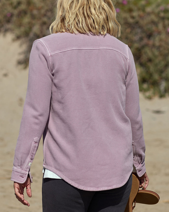 Person wearing a light pink pastel blanket shirt on a beach